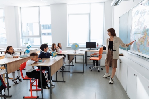 teacher at the front of a classroom teaching students at desks
