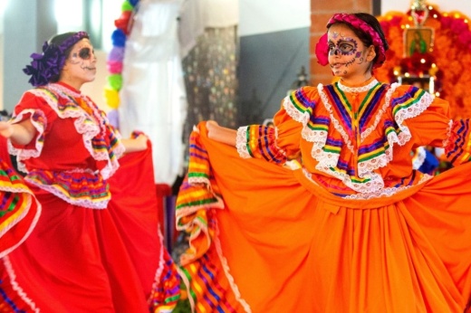 Girls dressed in traditional dresses perform with face paint for Dia de los Muertos