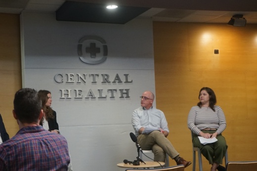 two people sitting in front of a central health sign