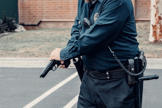 An officer holds a gun; the head of the officer is not pictured
