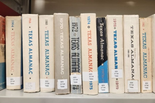 A handful of Texas Almanac books sit on a shelf at a library.