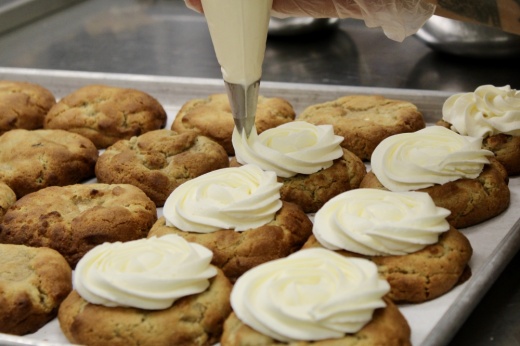 cookies being frosted with white frosting