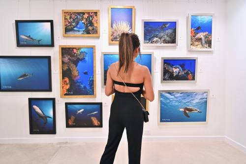 A woman stands in front of a wall of aquatic art.