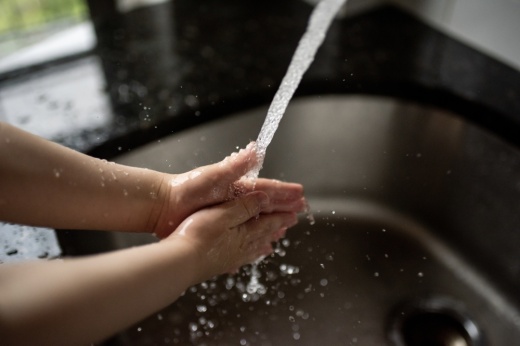 Cropped image of child washing his hands. Water splashes all around.
