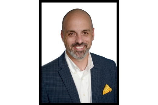 A headshot of Mark Koller shows a bald man with a beard in a black blazer with a yellow handkerchief.