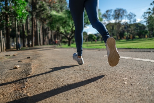 A runner is running on a roadway with trees