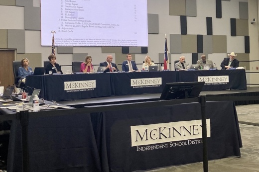 a group of people sit behind a row of tables on a small stage