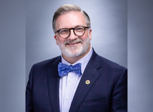 A headshot of ACC Chancellor Russell Lowery-Hart shows a man with gray and white hair wearing glasses in a suit with a bowtie.