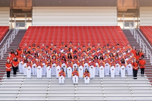 a large group of band kids standing on stadium seats
