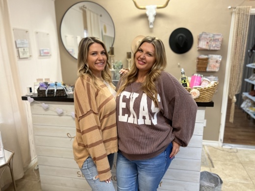 two women pose in a salon space