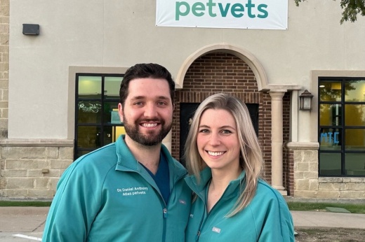 two people stand outside of the atlas pet vets builsing