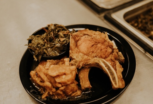 A plate of fried pork chops with collard greens is shown on a table.