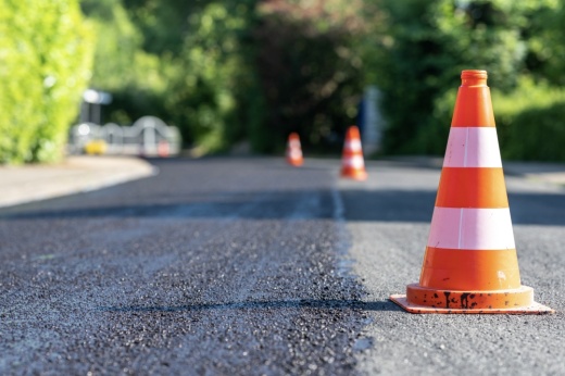 Construction cones marking part of road with a layer of fresh asphalt.