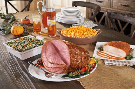 Ham, turkey, green beans and other dinner items on a table.