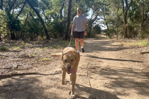 Braon Moseley and his dog, Bear, walk the trails at Southwest Williamson County Regional Park, which would be extended to connect to the intersection of RM 1431 and Sam Bass Road using bond funds. (Claire Shoop/Community Impact)