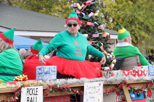 A person dressed as an elf with a red tutu poses on a parade float outside during a previous Christmas parade.