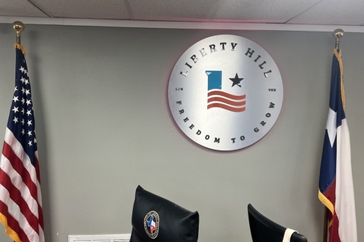 Liberty Hill seal on the wall in between the U.S. flag and Texas flag