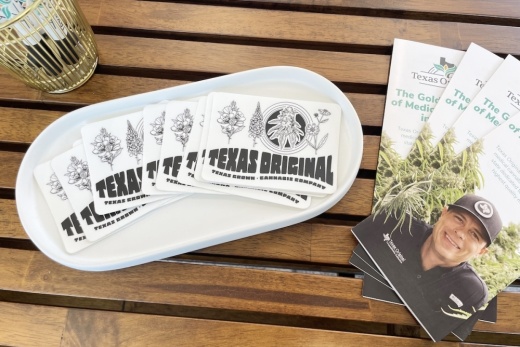 A brown wooden table holds pamphlets and stickers for Texas Original.
