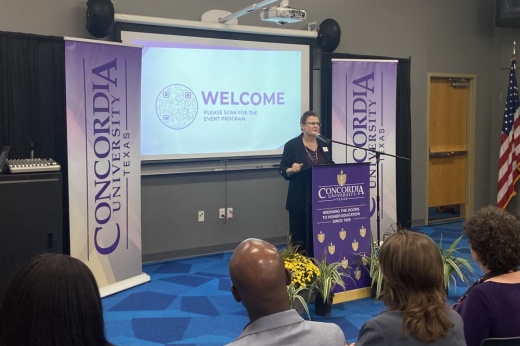 A female university provost delivers an address behind a podium at Concordia University Texas.