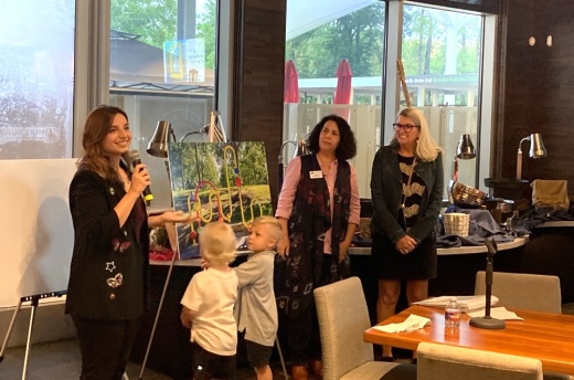 A woman stands in front of artwork with her family