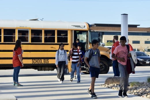 a group of students walk away from a school bus