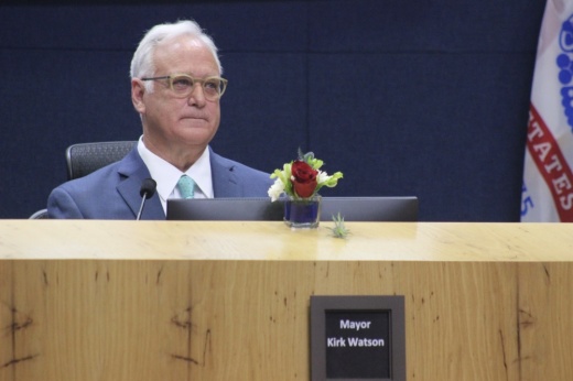 the mayor seated behind a computer and dais