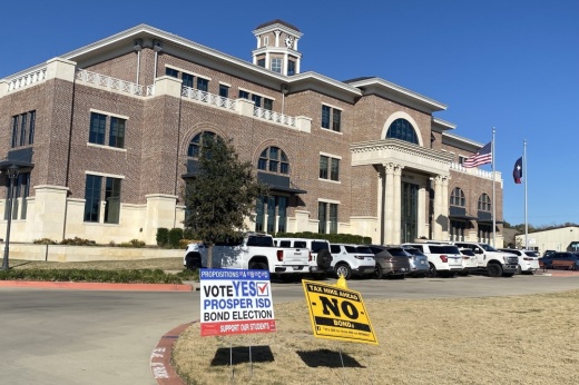 Prosper Town Hall with two signs in front, one for an election one against