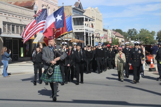 Men and women march in uniform along downtown Bastrop.