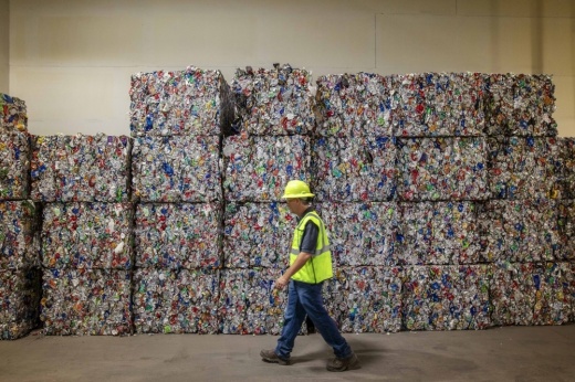 Lester Dalrymple, recycling manager at the WM Westside Material Recovery Facility, walks alongside a wall of compressed bales of recyclable materials