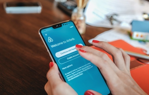 Female hand holding smartphone with Airbnb application