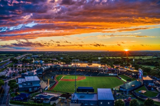 Sun setting over Dell Diamond ball park with an orange and purple sky.