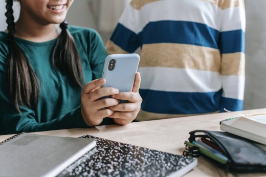 a girl holds up a phone to show a classmate