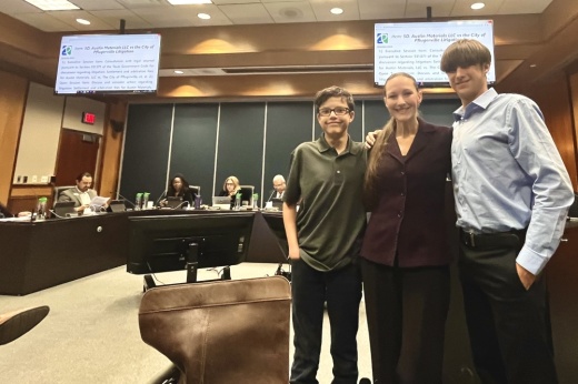 Three members from a nonprofit stand before city council presenting their goal to eliminate alternative lunches in local schools.