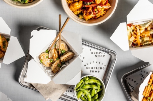 A table is filled with dumplings on silver trays.