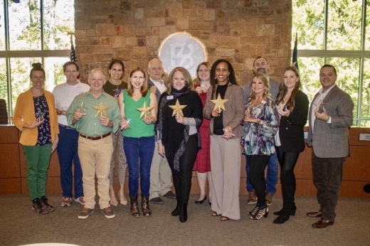 A group of adults hod four star while posing for a photo.