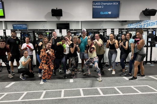A group of people pose inside the gym in front of the mirror.