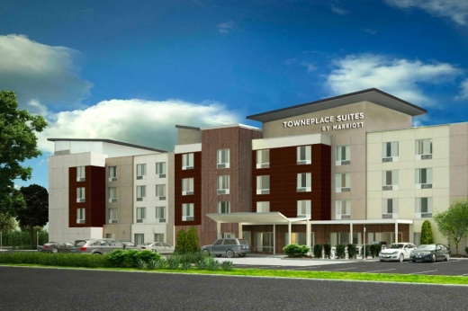 Site rendering for a new hotel in hutto show the front of.a four-story, 89-room grey and coffee brown building.