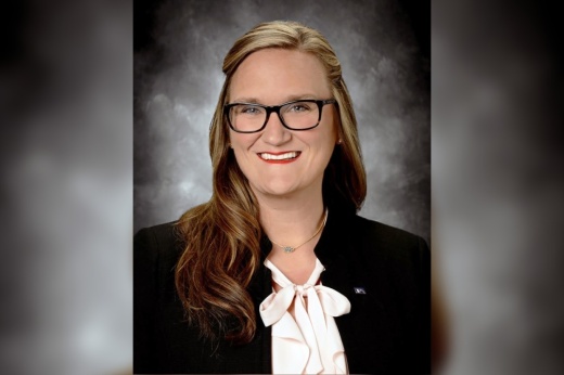 a headshot of a woman wearing a suit and glasses