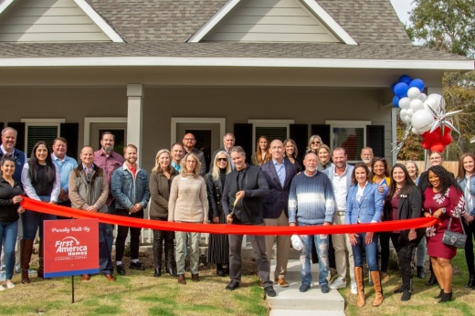 People stand in front of a ribbon during a ribbon-cutting ceremony
