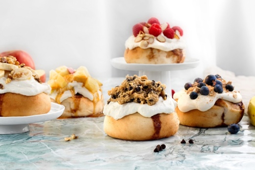 several cinnamon buns are positioned on a table and on small pedestals