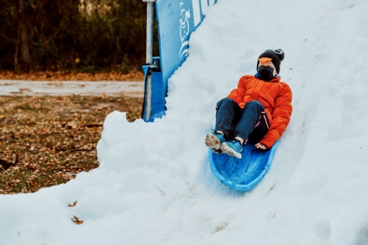 A kid sledding down a snow hill