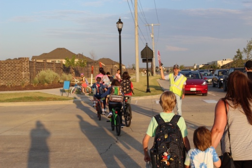 kids on bikes and walking cross a street on the way to school