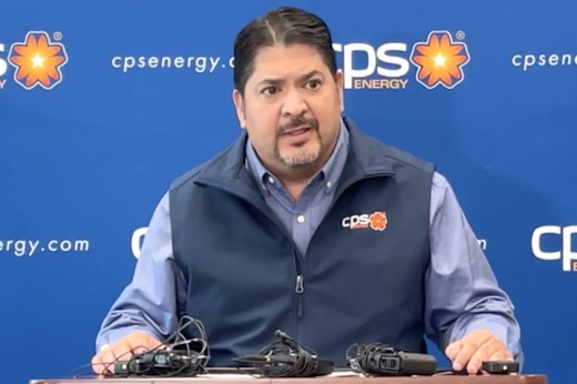 man stands at a podium in front of a blue backdrop