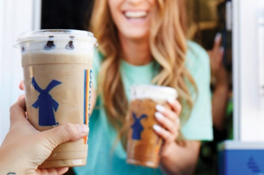 person handing coffee cups through a drive-thru window