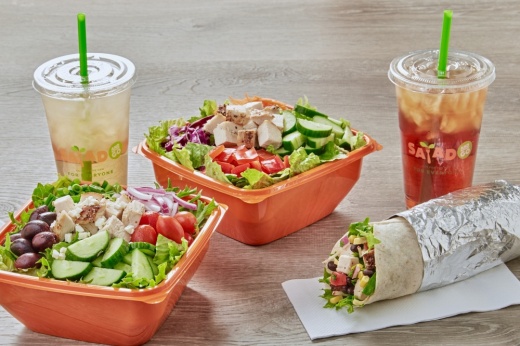 Two drinks, two salads and a wrap sitting on a table