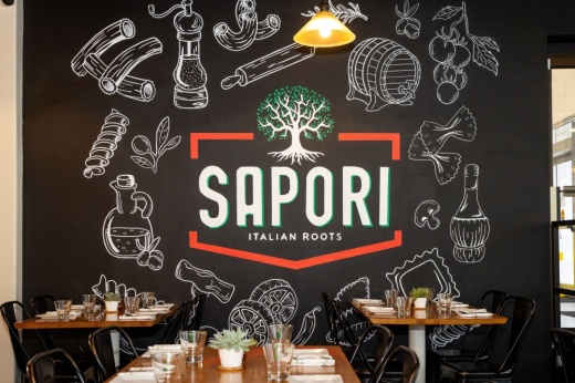 A black wall has the Sapori logo on it, tables for diners are placed in the foreground.