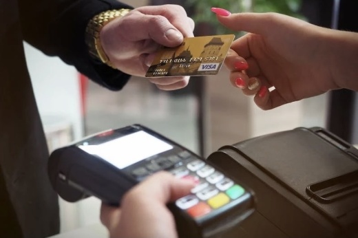 a customer hands a credit card to a banking clerk