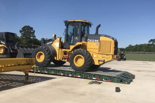 a truck unloads a John Deere tractor