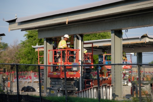 A construction employee stands on a machine platform at Addison Transit Center