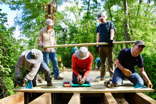 People work on a wooden boardwalk in the woods